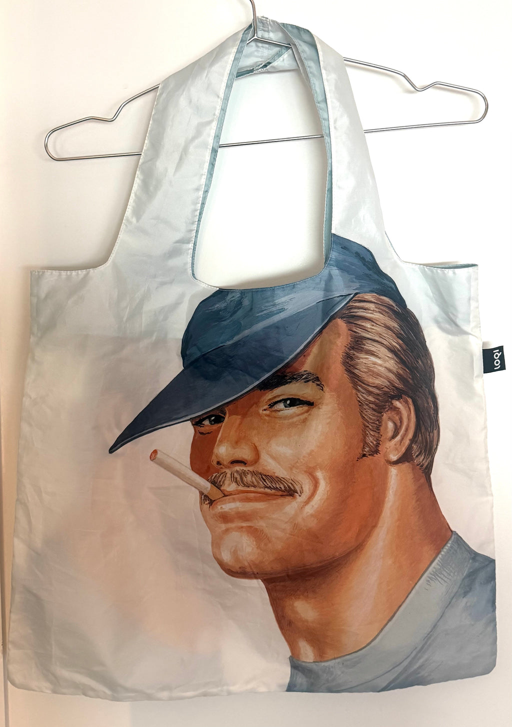 Prototype LOQI tote bag printed with a Tom of Finland portrait of a man in a blue cap