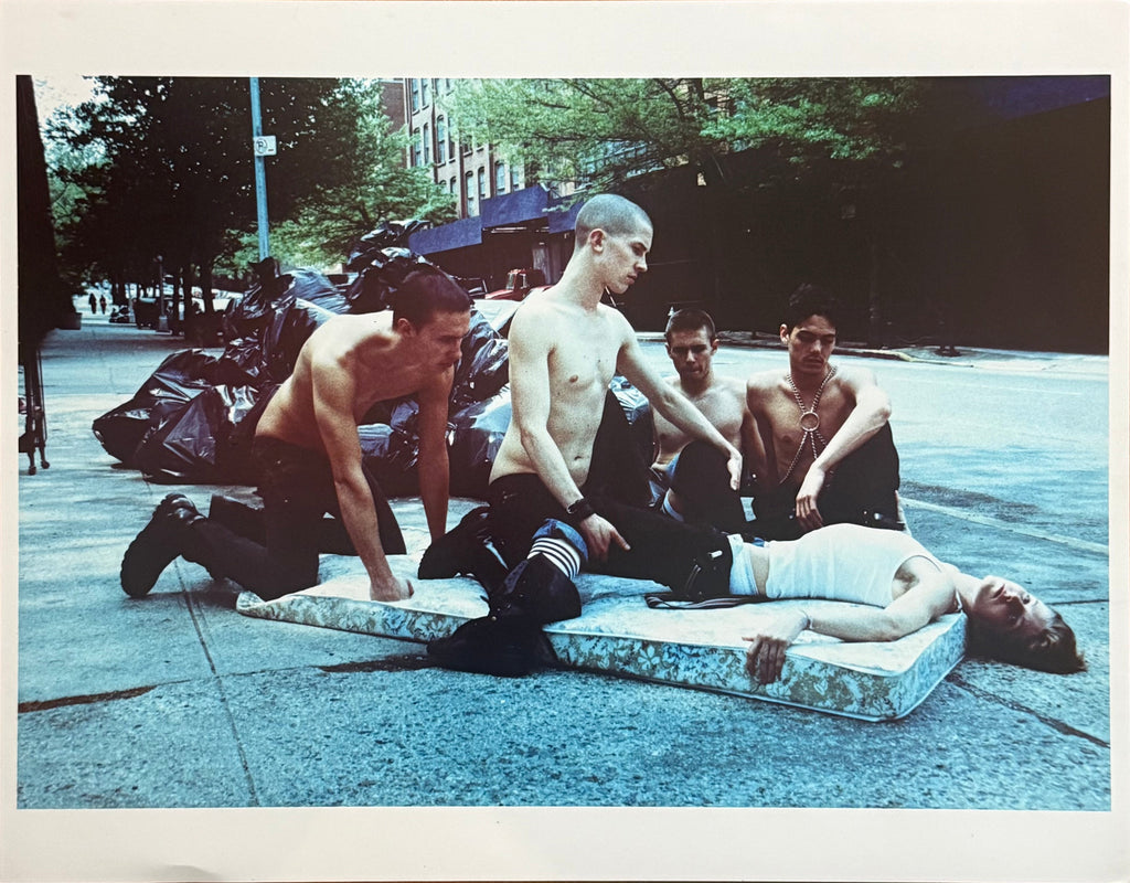 Colour photograph of five young men gathered on a discarded mattress on a New York sidewalk